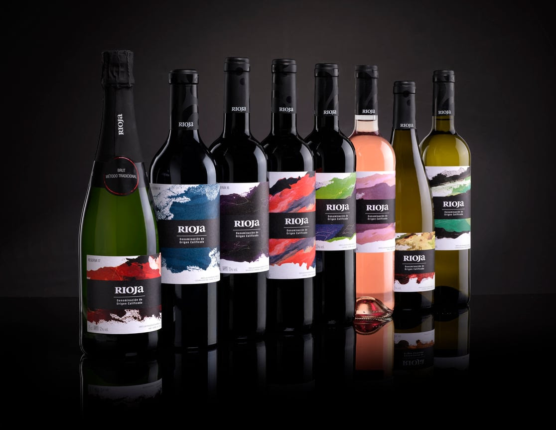 Ocho botellas de vino Rioja sobre un fondo negro.